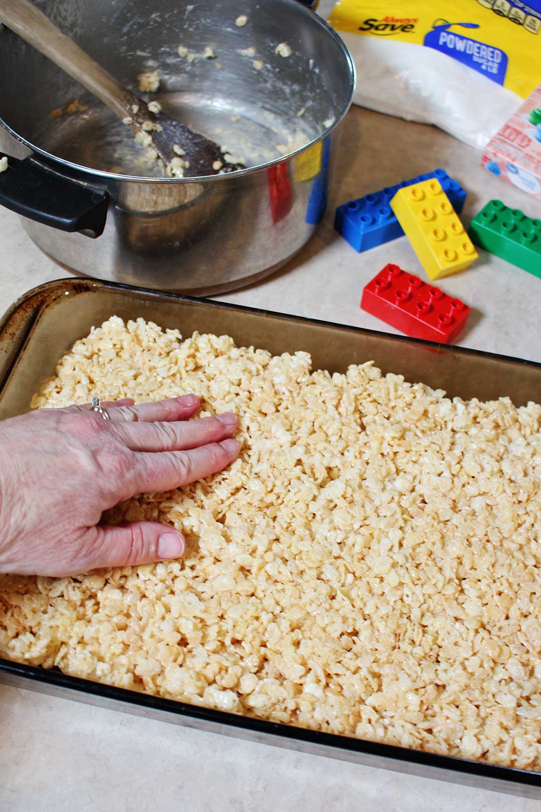 Pressing down a rice crispy mixture into a pan.