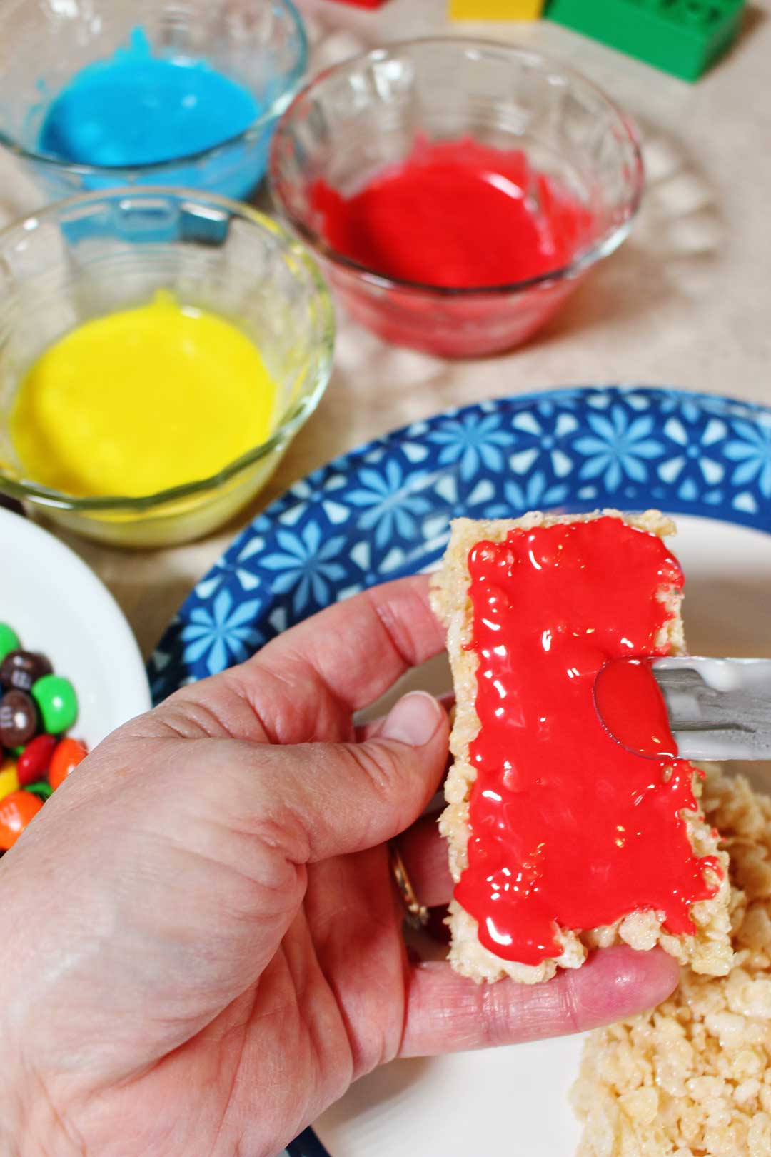 Adding red frosting to a rice crispy treat rectangle.