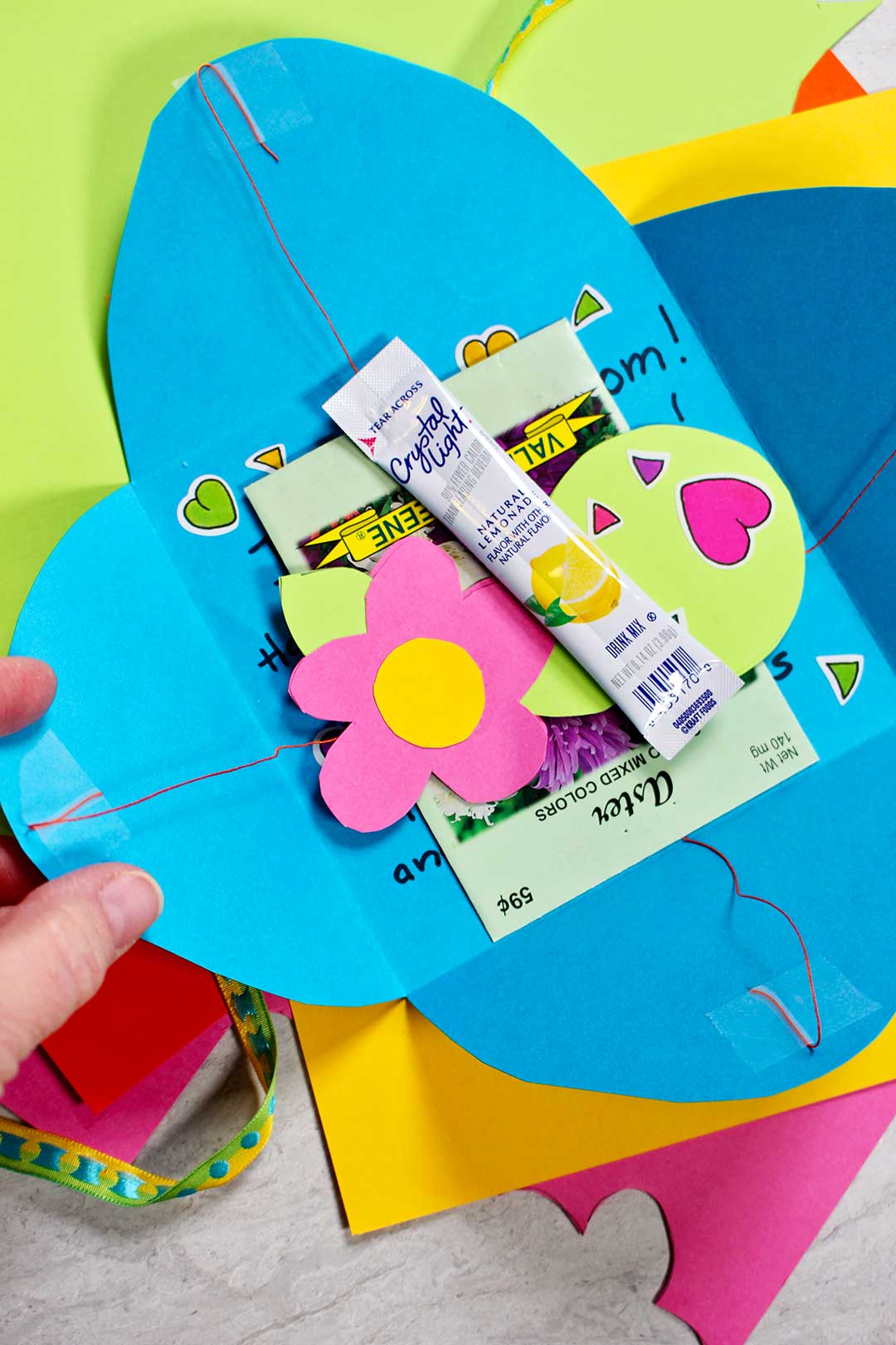 A homemade card with a paper flower, stickers, a drink packet, and seed packet inside.