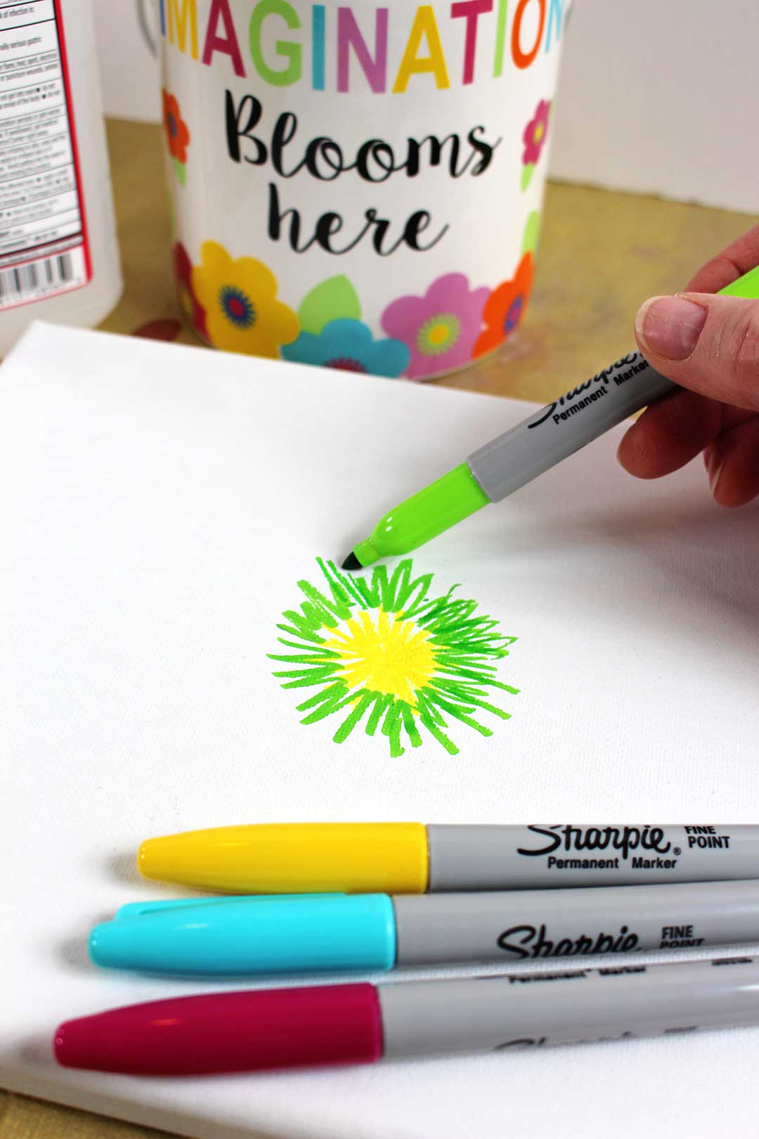 Coloring bright lines on a canvas with a green sharpie marker.