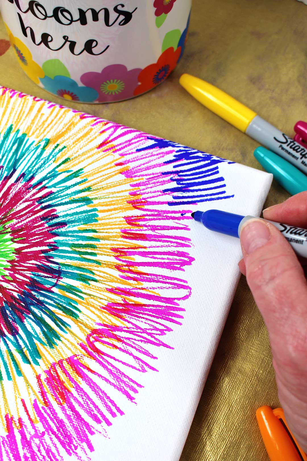 Coloring bright lines on a canvas with a blue sharpie marker.