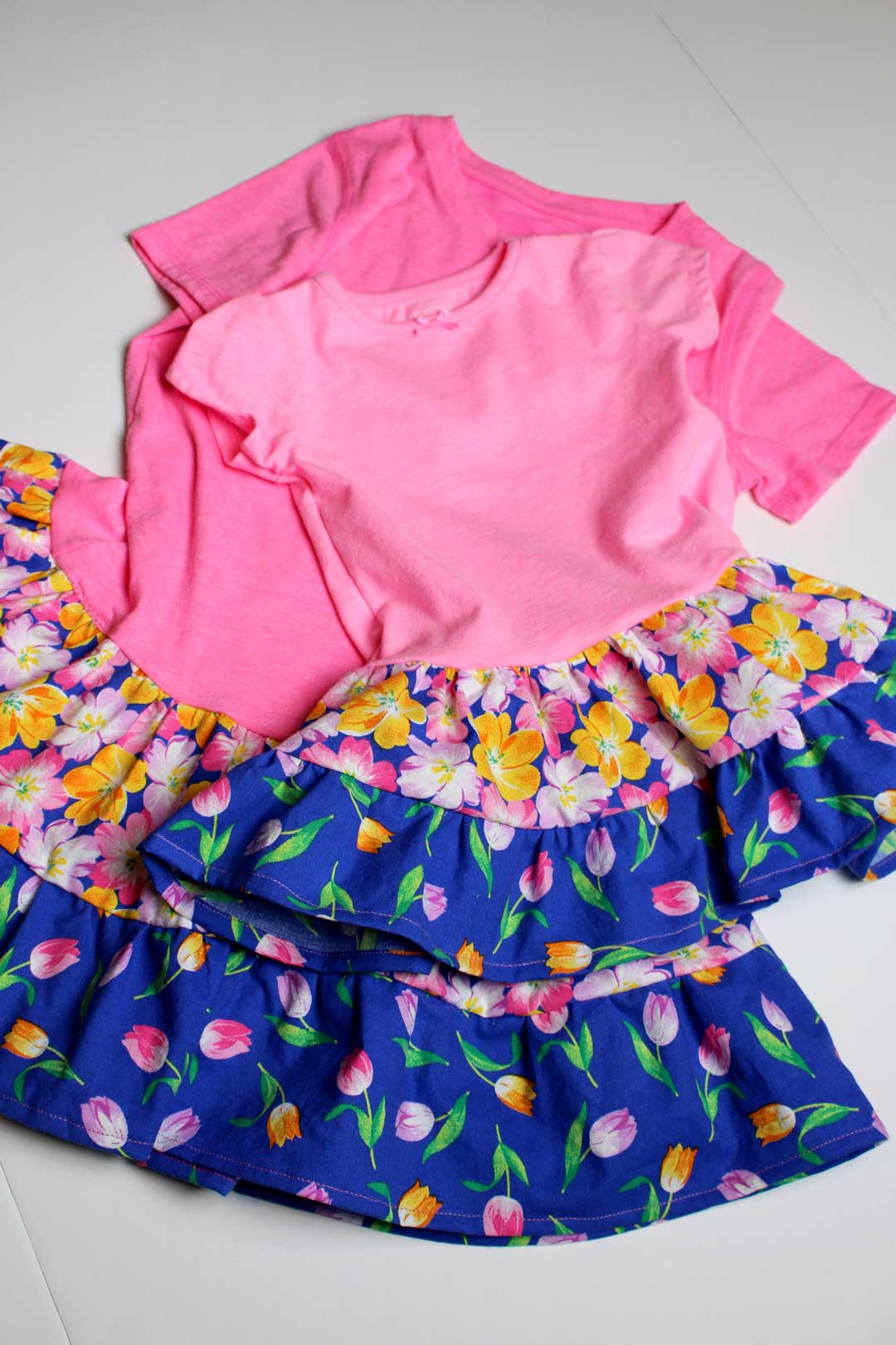 Two pink and floral homemade T-Shirt dresses displayed on a table.