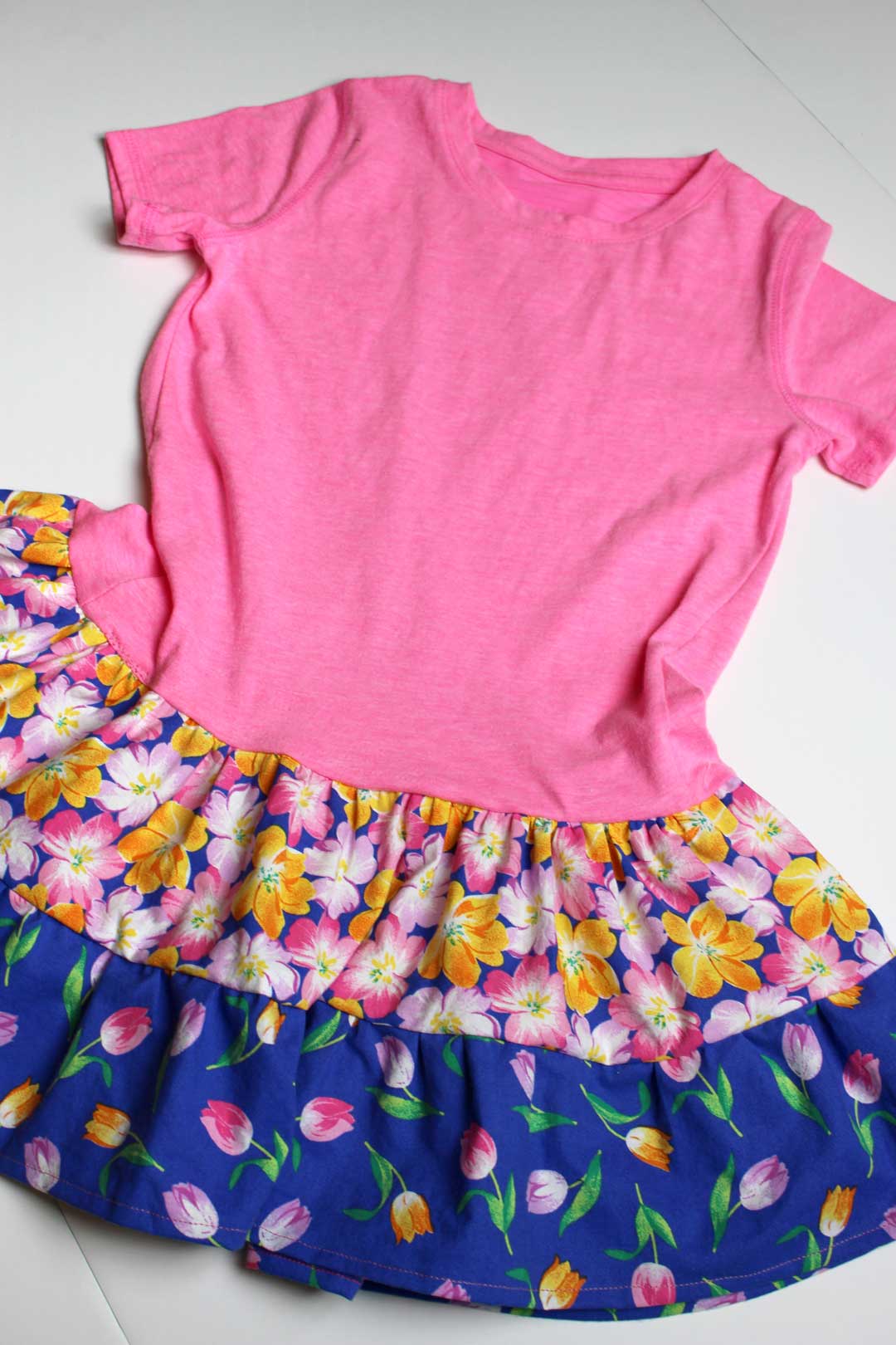 A pink t-shirt sewn to two floral layers of fabric made into a skirt, to make a t-shirt dress.