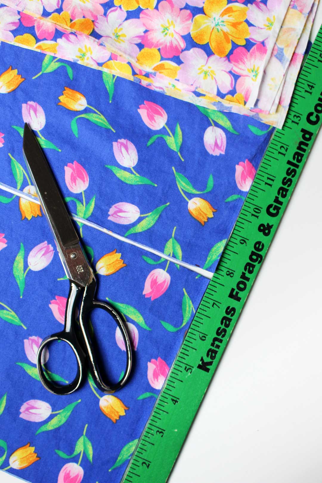 Floral fabric laying next to a ruler with a pair of fabric scissors nearby.