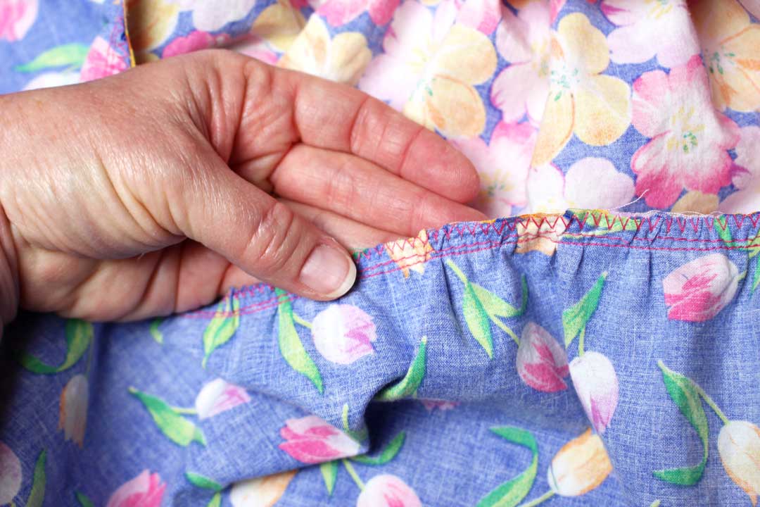 A zigzag stitch along the edge of several layers of floral fabric. 