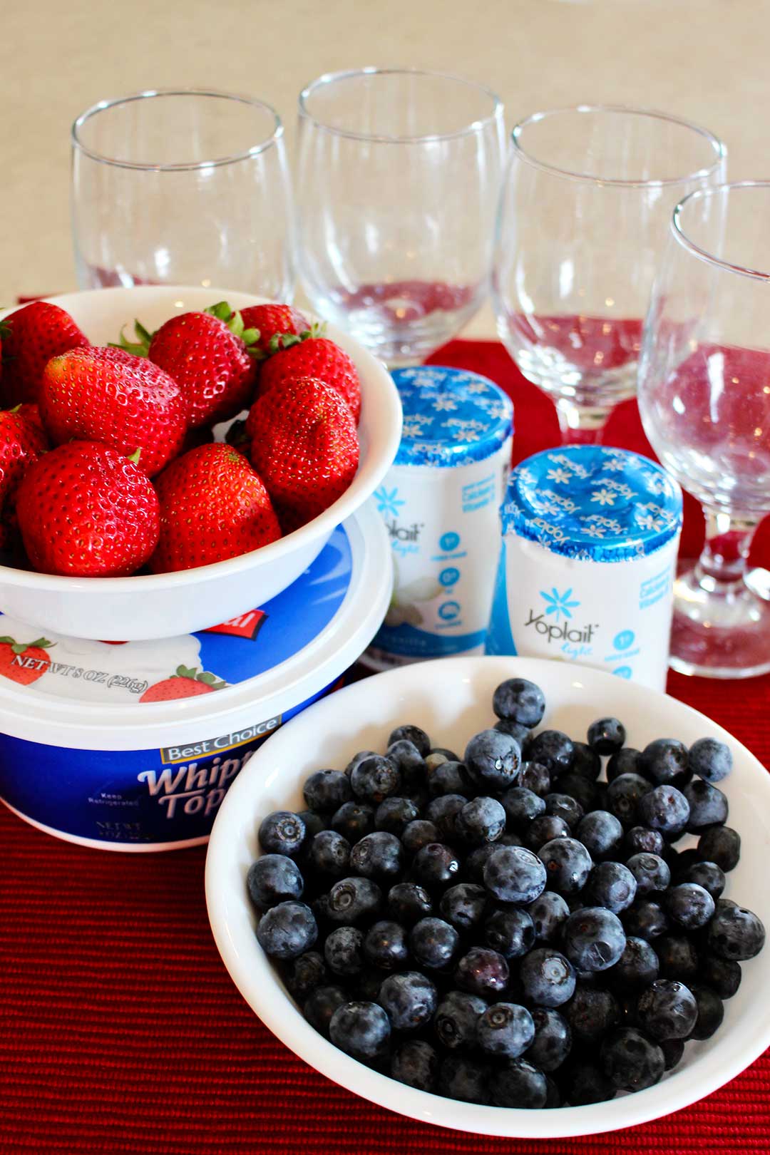 Blueberries, strawberries, yogurt, whipped cream, and glass parfait cups.