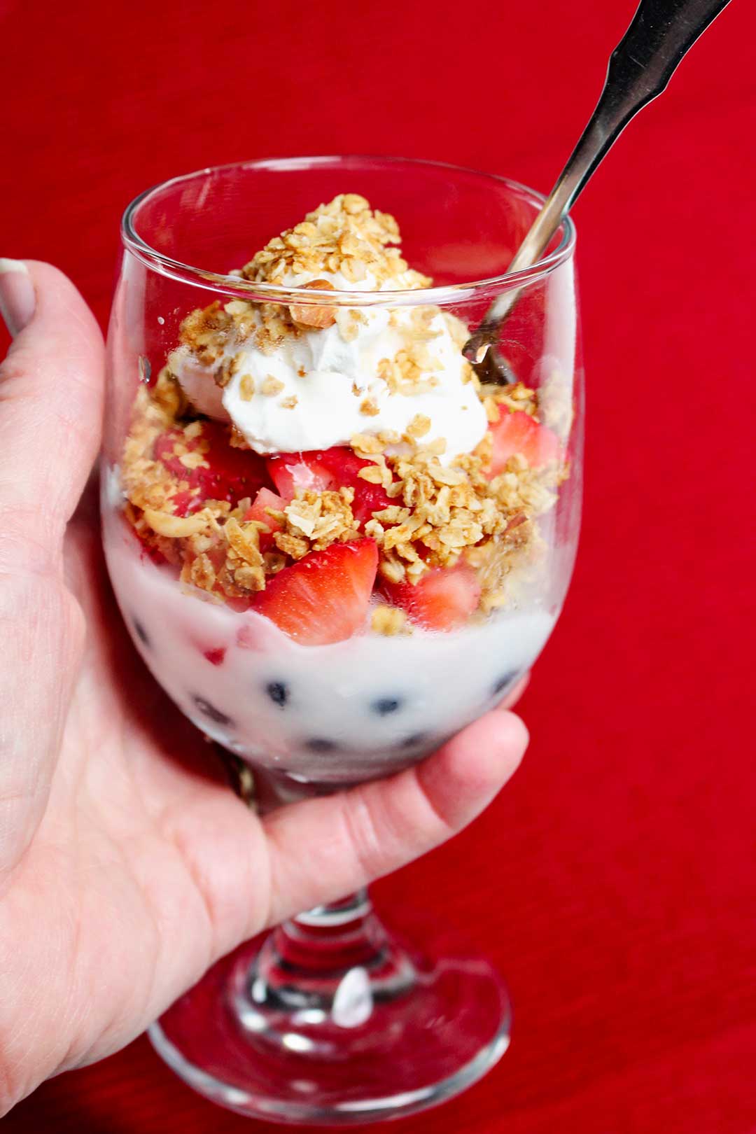 Red white and blue fruit parfaits with blueberries, strawberries, granola, and yogurt.