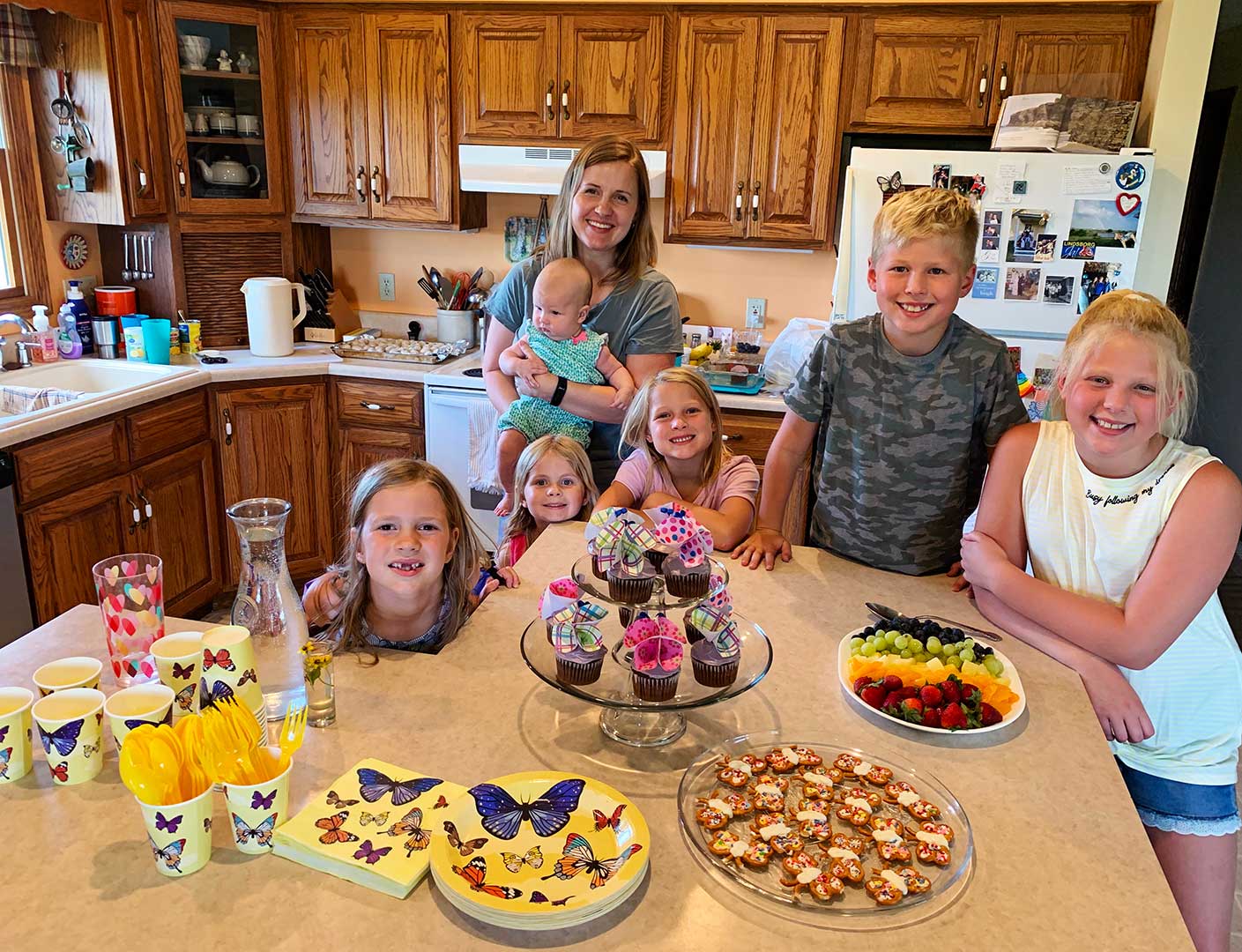 Children standing around snacks prepared for a Butterfly themed birthday party.