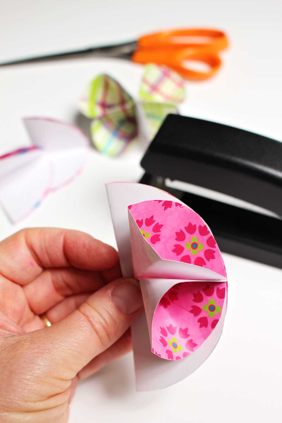 Several circles of pink and green paper stapled together.
