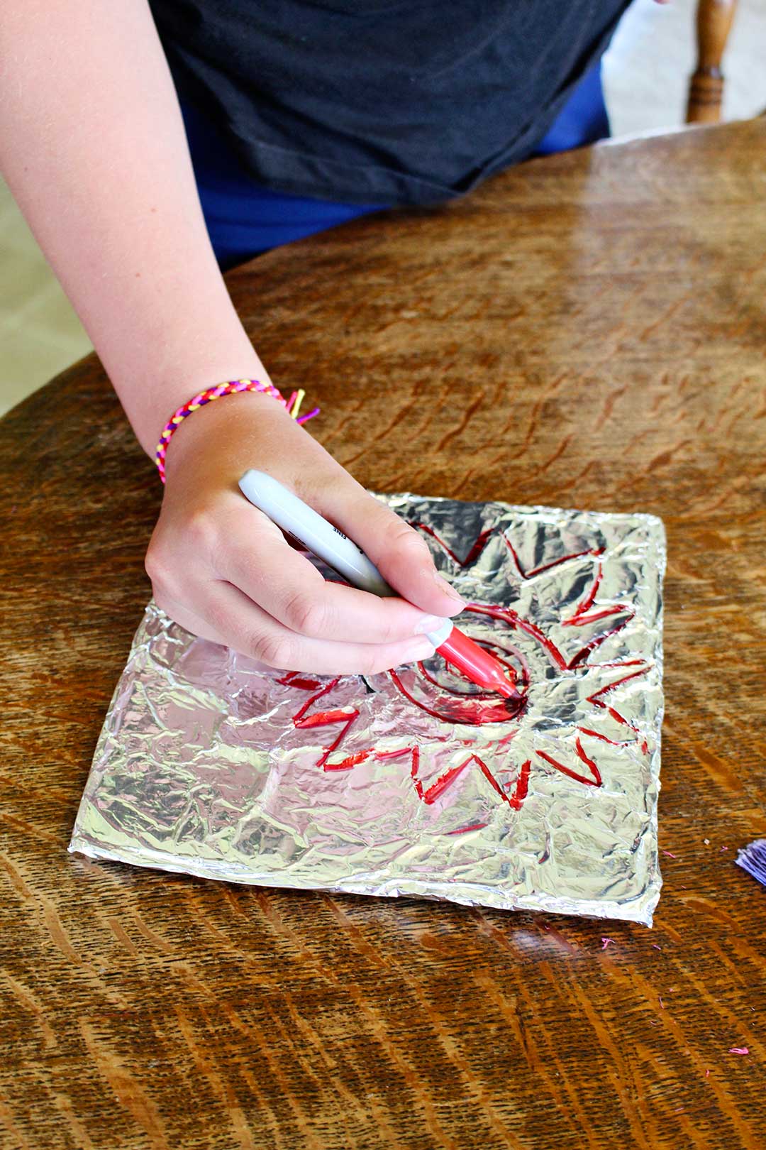 A child coloring in the Aluminum Foil Embossed Art picture of a sun.