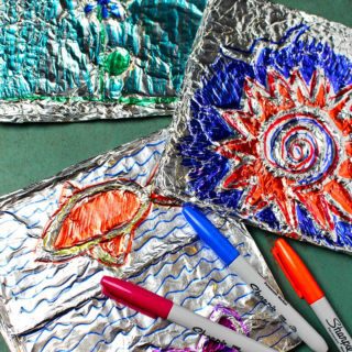 Sharpie markers laying on three colorful Aluminum Foil Embossed Art projects.