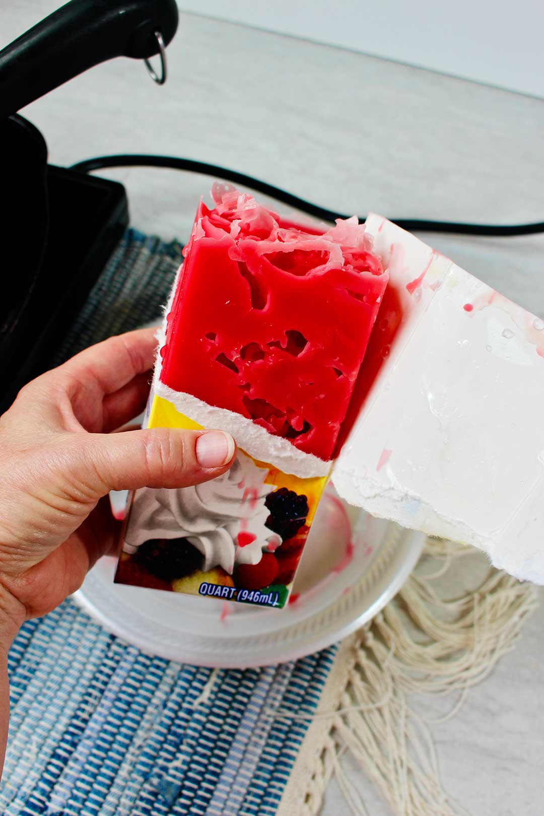 Person holding carton half ripped to show new candle made with ice cubes.