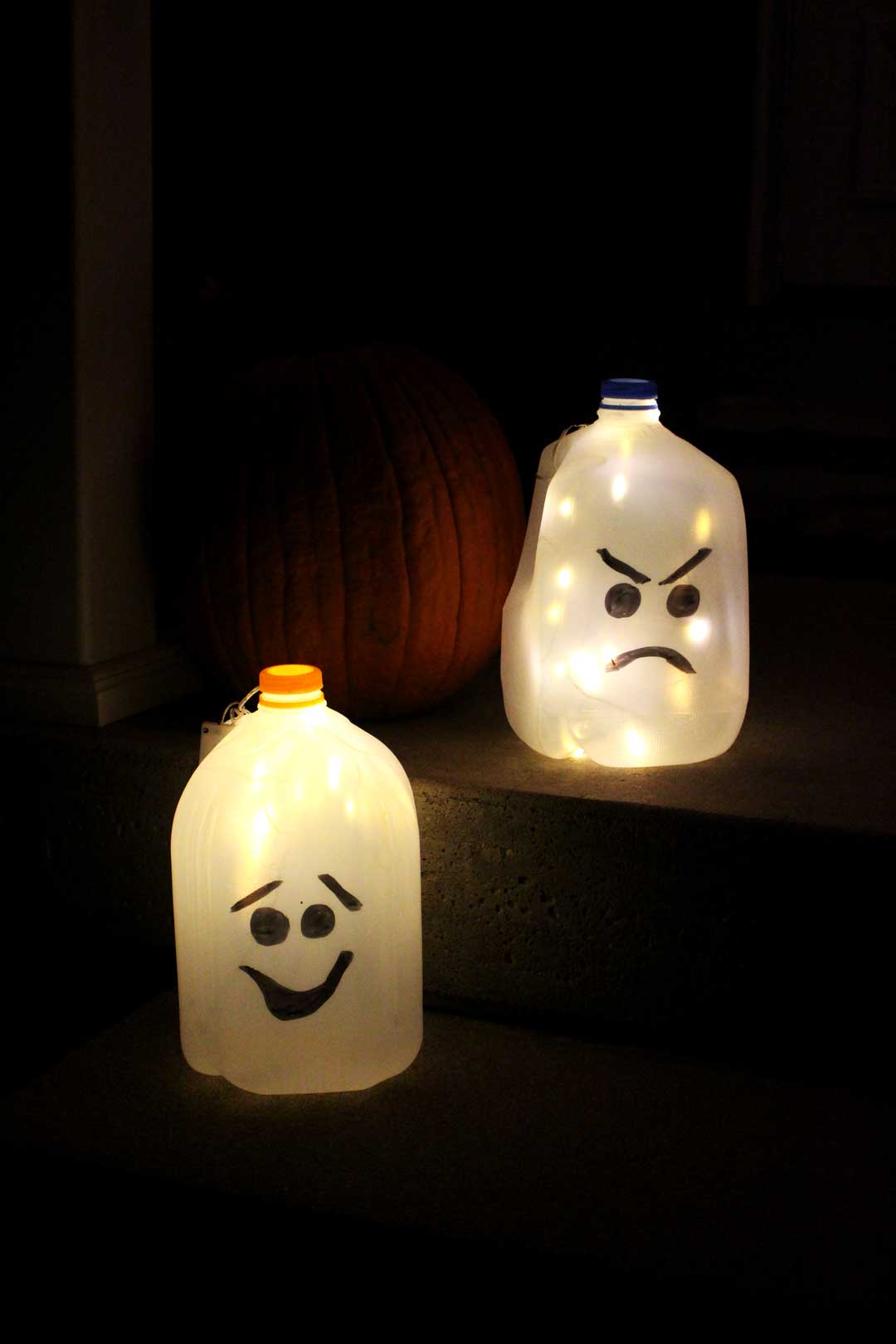 Recycled milk jugs with faces drawn on them to create glowing ghost luminaries.