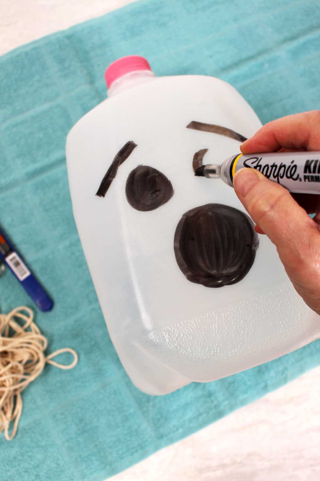 A sharpie drawing a ghost face on a recycled milk jug.