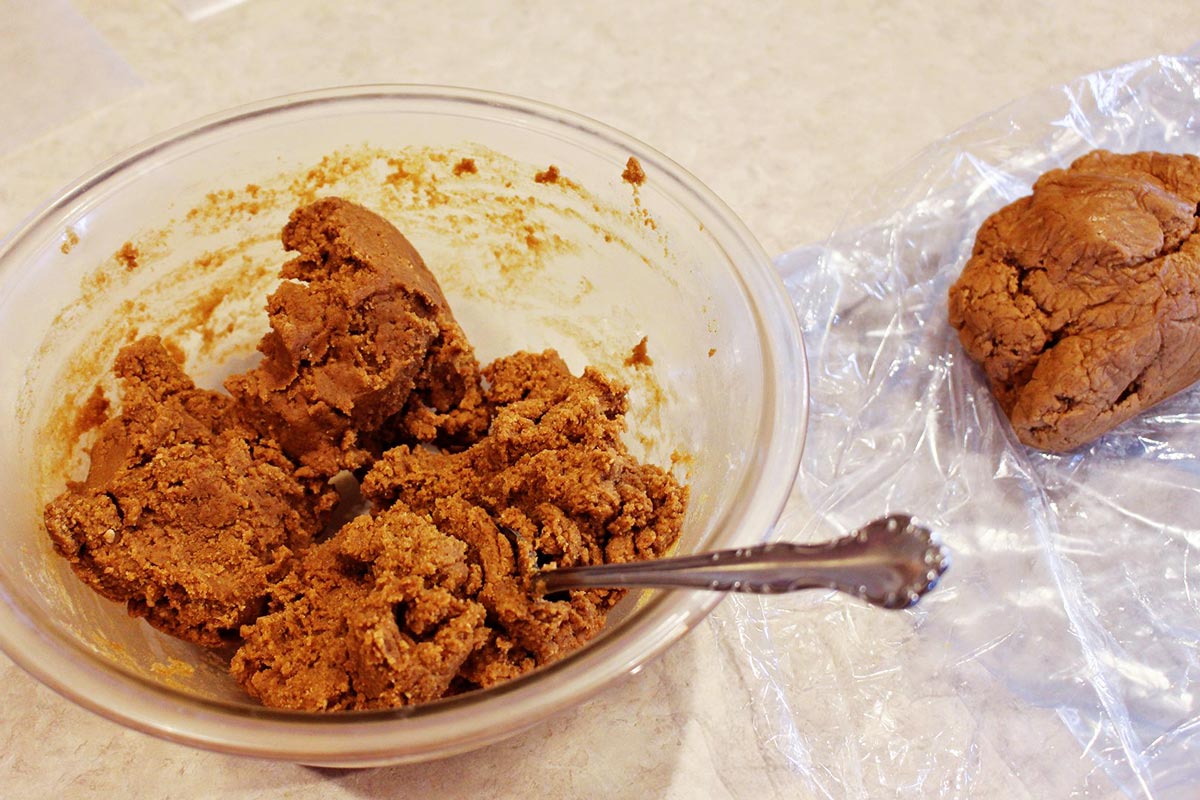 A bowl of gingerbread cookie dough in a bowl with a mixing spoon