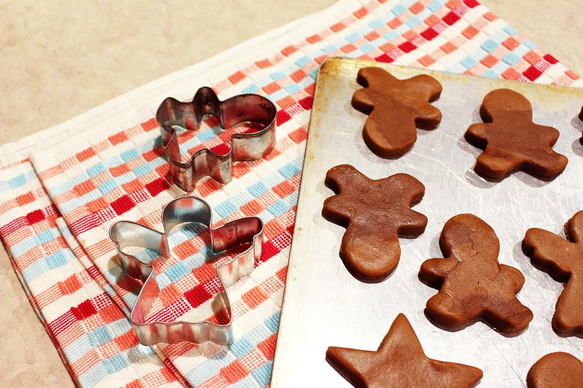 Christmas cookie cutters and cut out gingerbread cookies on a baking tray