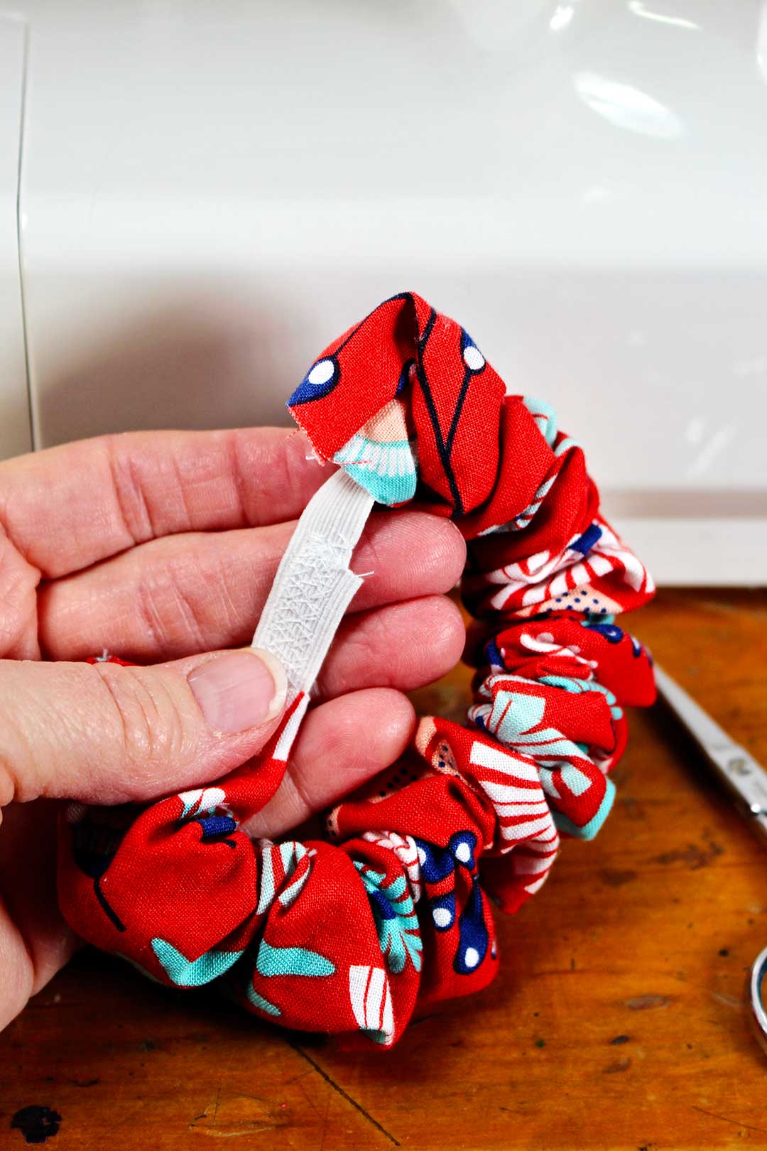 Person holding red patterned scrunchie showing elastic inside.