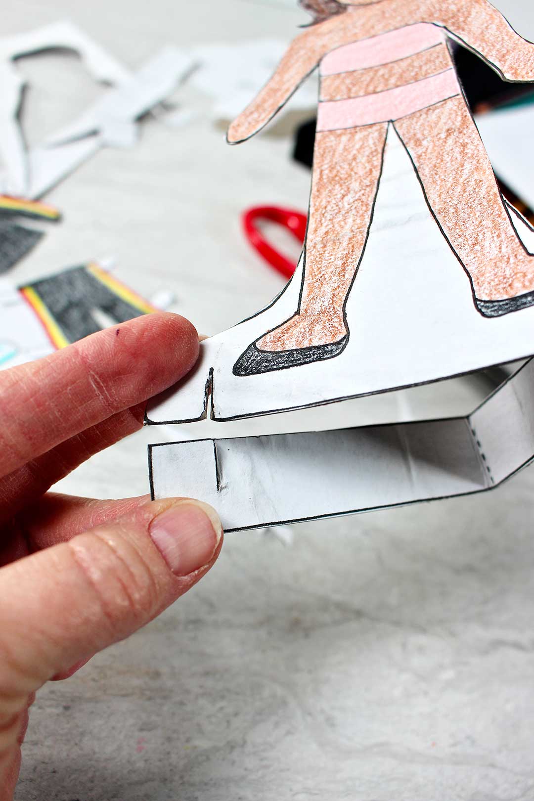 Close up view of person putting together paper doll base.