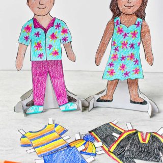 Male and female paper dolls, colored and dressed on their bases. Colored pencils and other colored clothing options nearby.