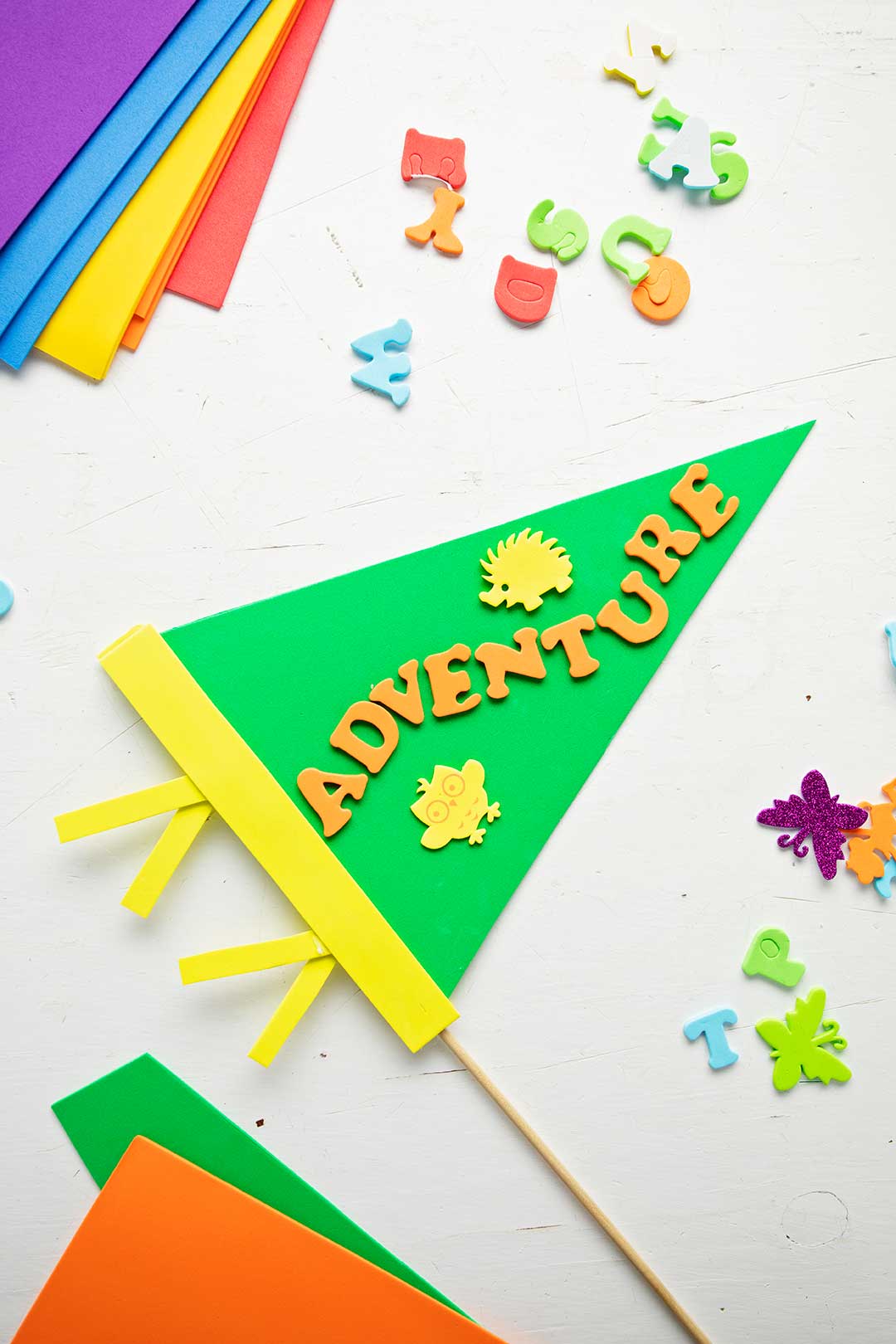 Green pennant decorated with "adventure" and various foam supplies resting on a white background.