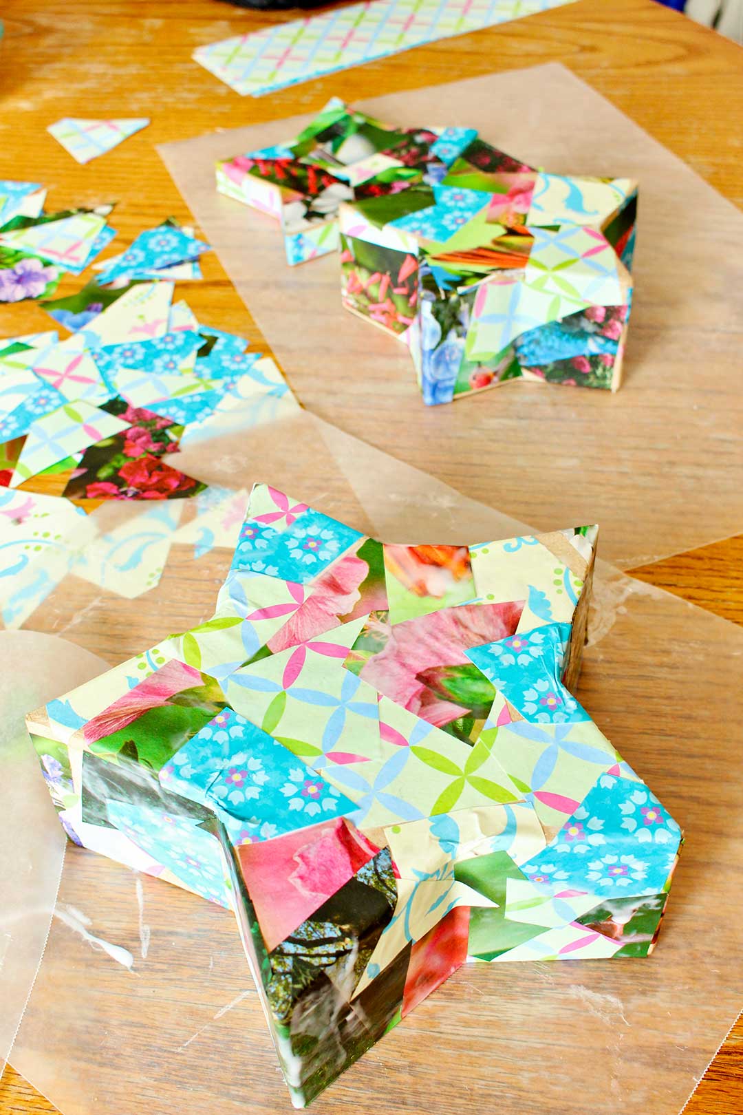 Completed decoupaged boxes resting on wax paper at the kitchen table.