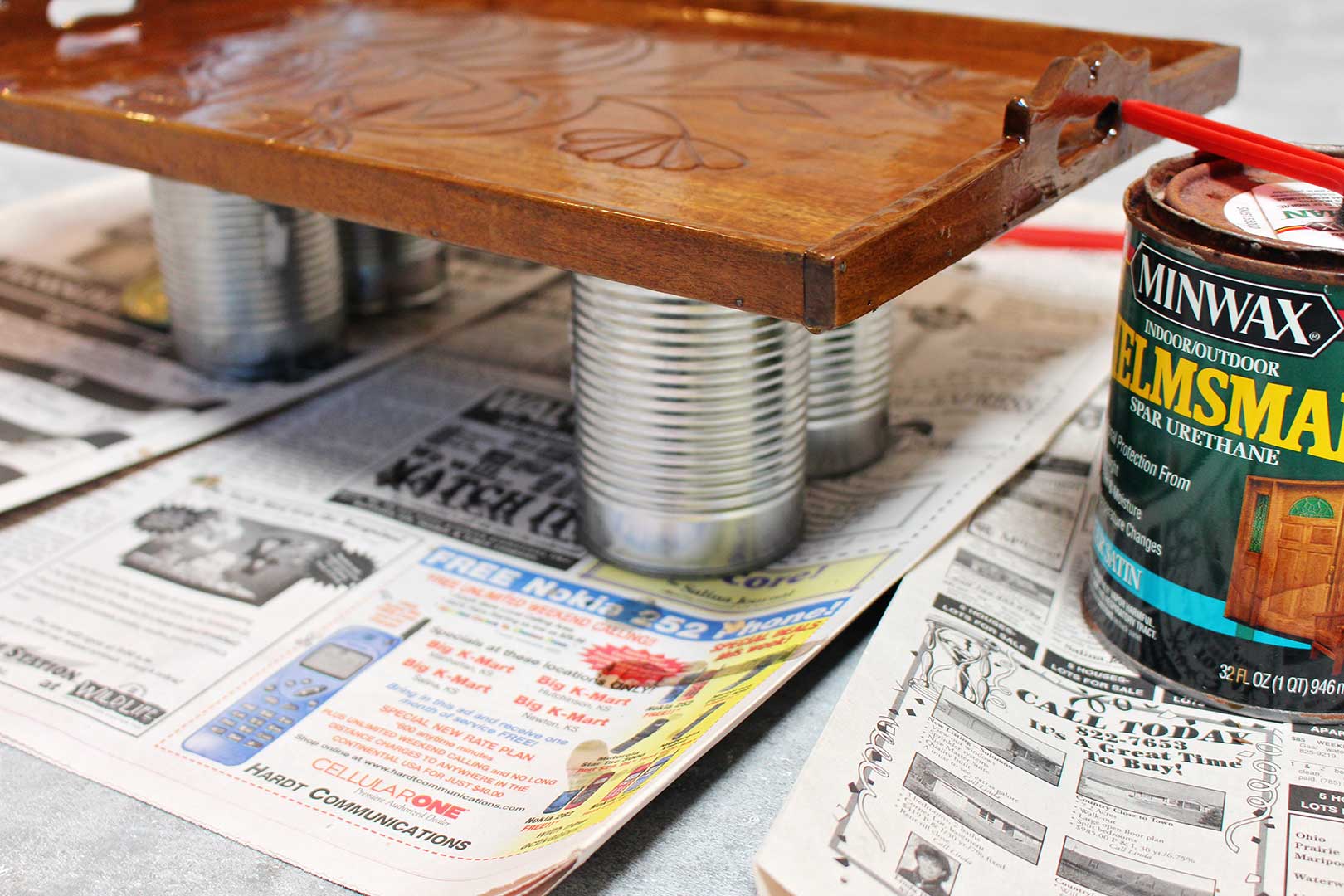 View of painted wood tray resting on tin cans for drying.