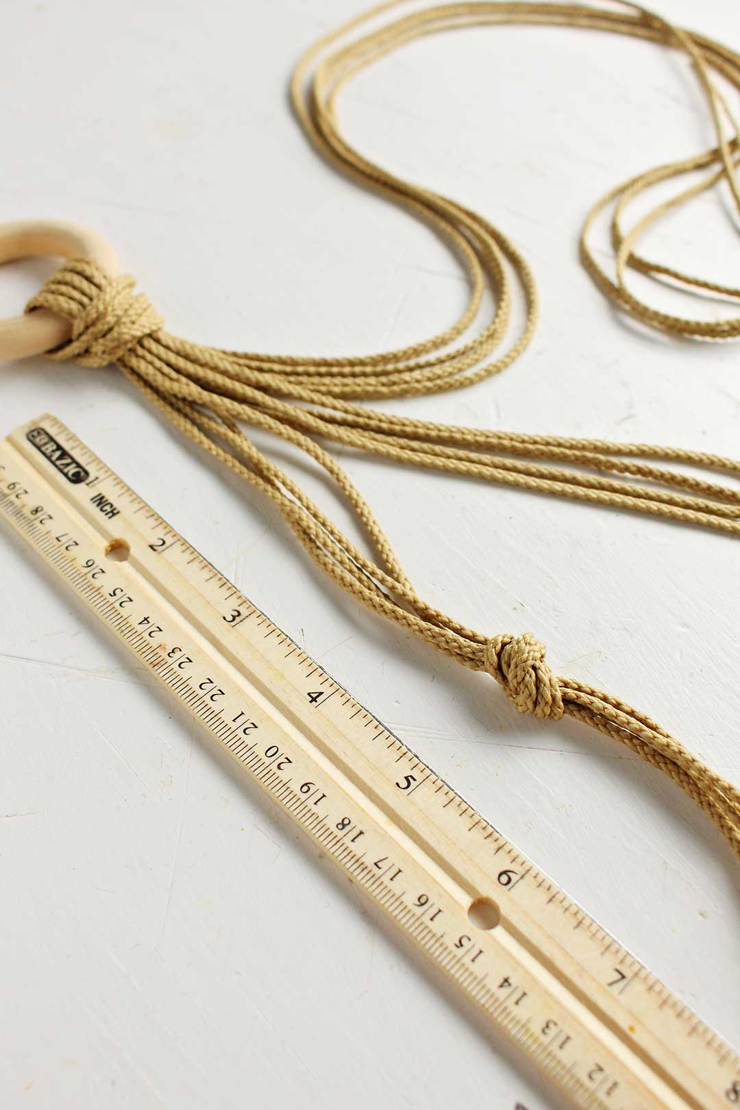 Ruler and rope showing the first knot of the macrame plant hanger.