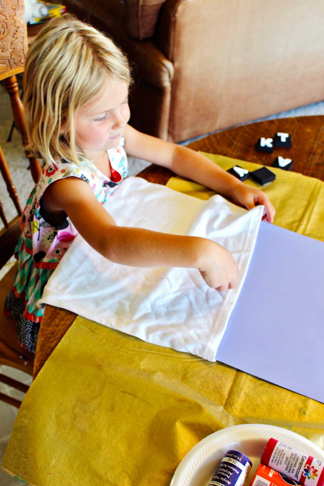 Une jeune fille blonde met du carton entre les T-shirts blancs pour éviter que la peinture ne colle ensemble une fois décorée.