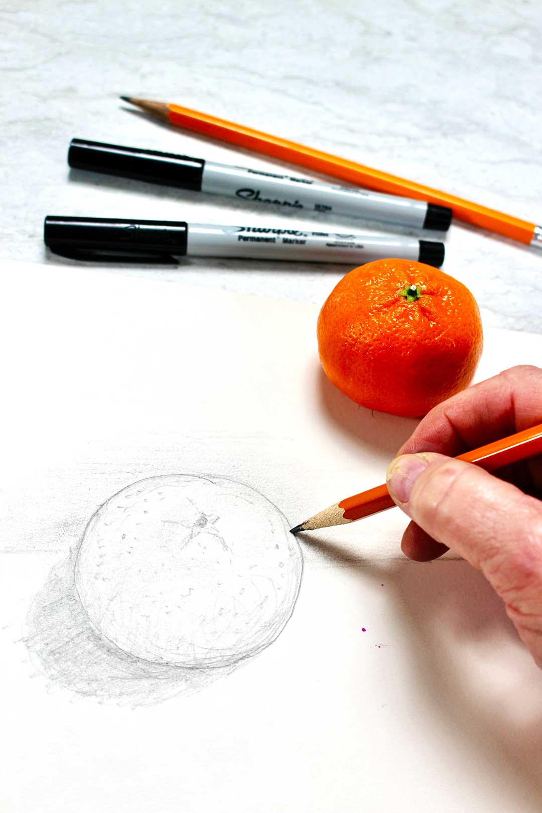 Close up pencil drawing of a 3D orange with two black sharpies, a clementine and a pencil nearby.