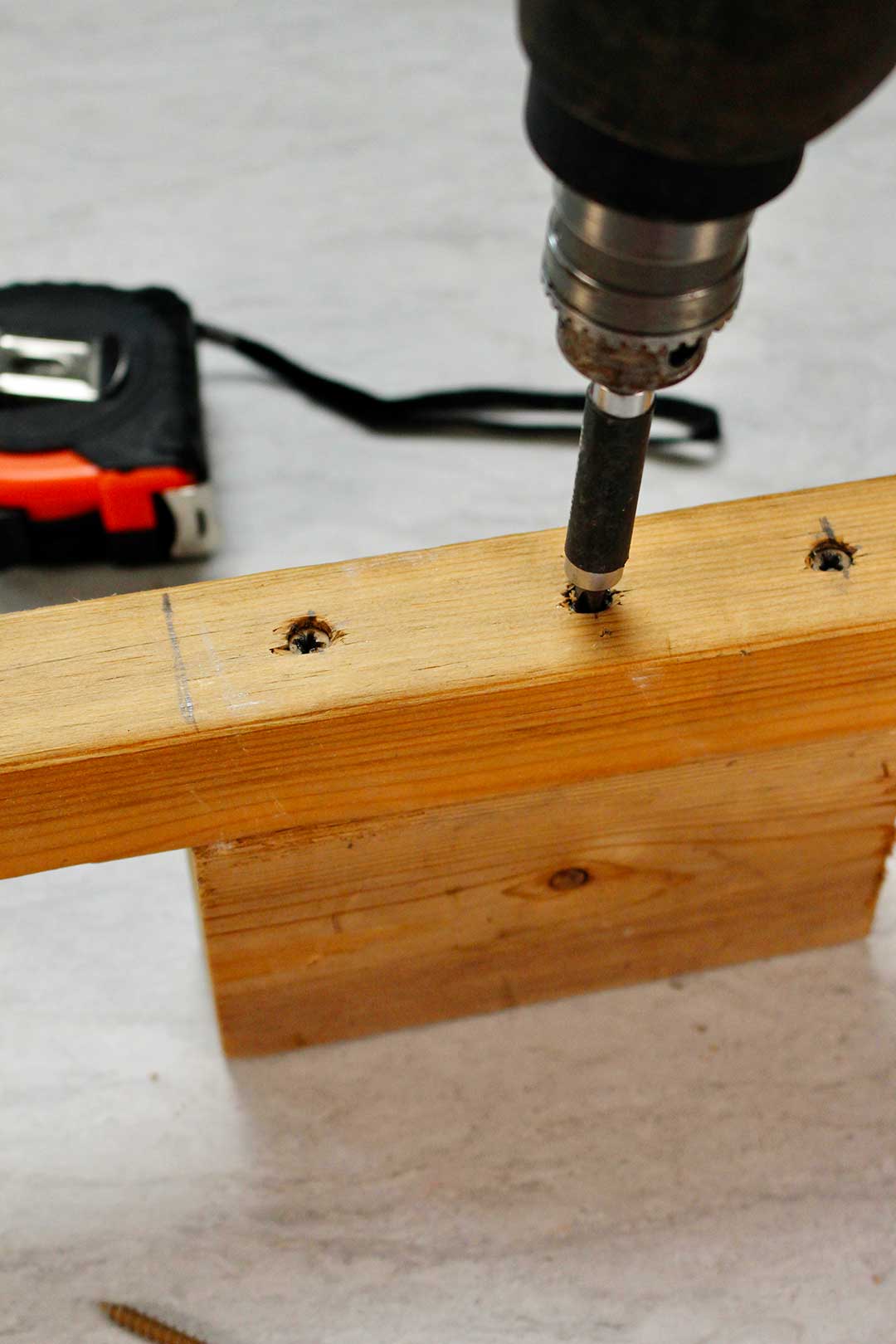 Close up image of drill screwing screws into wood pieces.