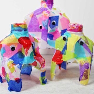 Three finished elephant crafts made from cut milk jugs decorated with tissue paper.