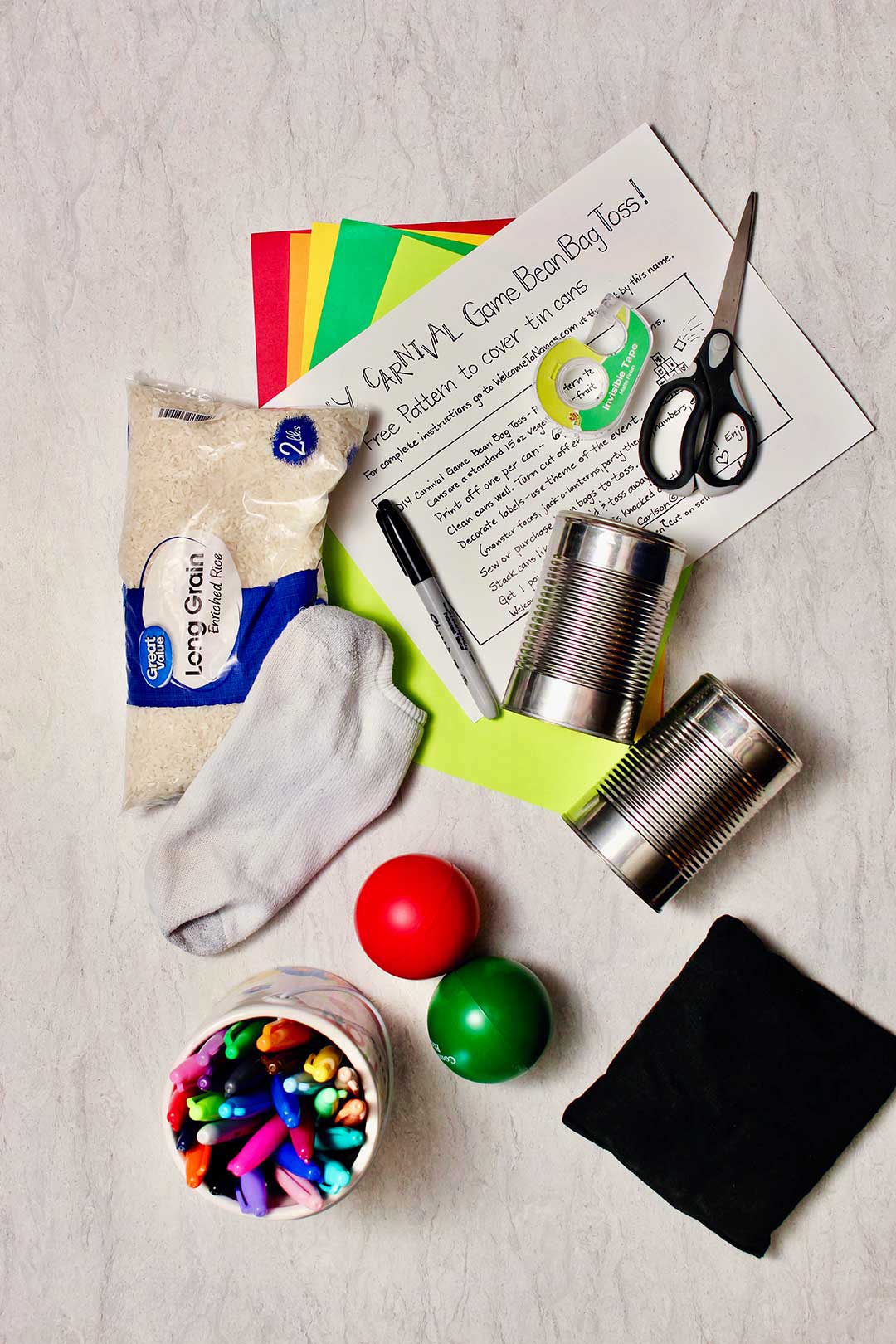 Supplies you would need for carnival games. Rice, a sock, tin cans, scissors, markers and paper.