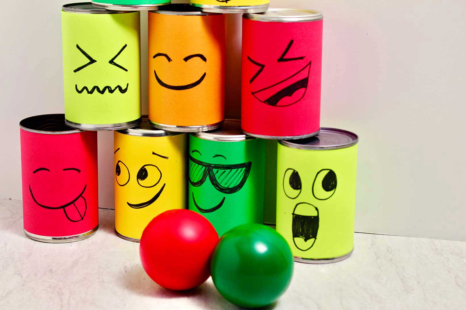 The lower portion of the stacked silly face tin cans with a red and green ball resting nearby.