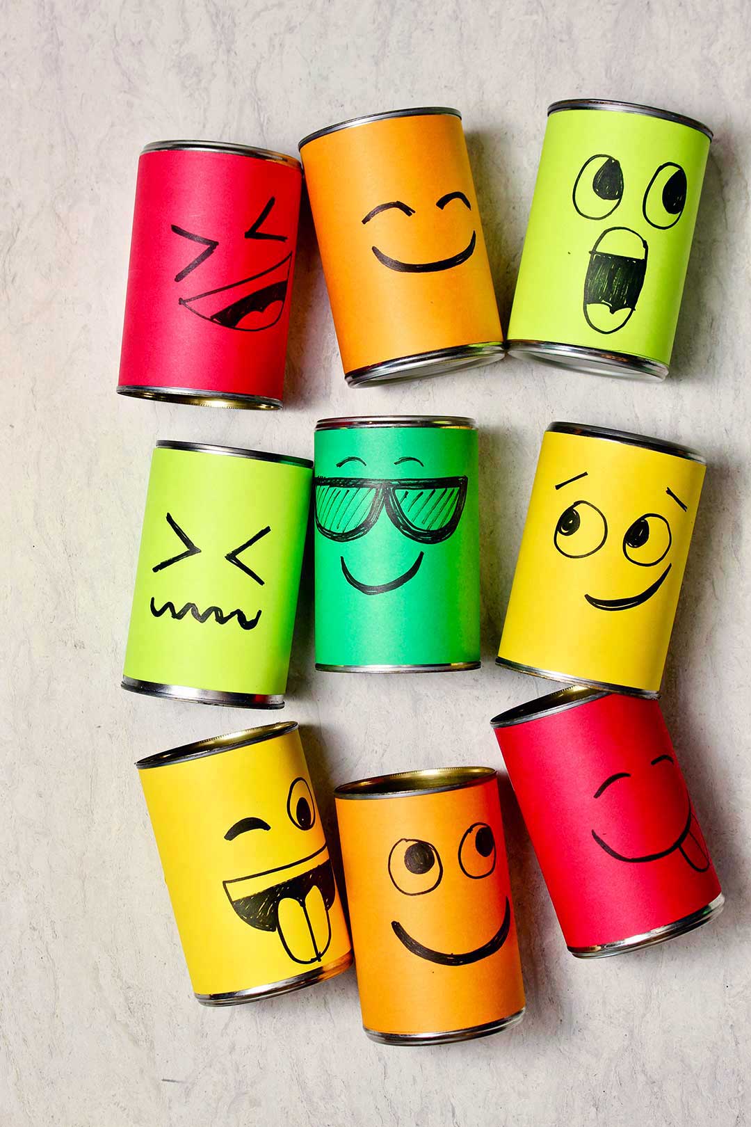 Nine different silly face cans resting on a marble background.