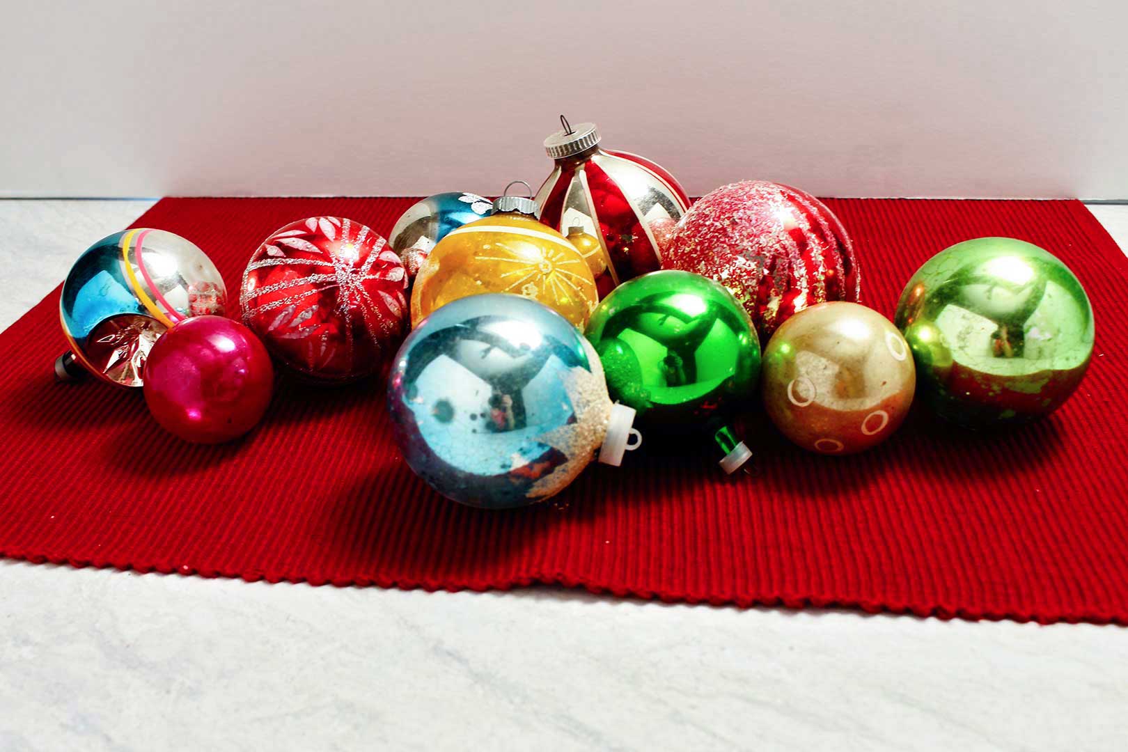 Christmas ornaments lay on a red placemat.