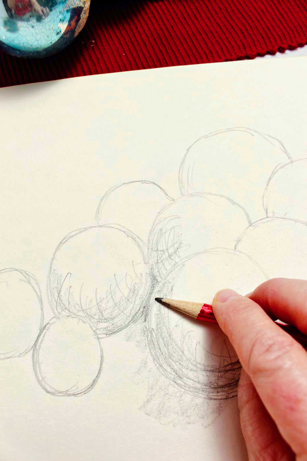 Close up view of a person shading their sphere drawing with pencil.