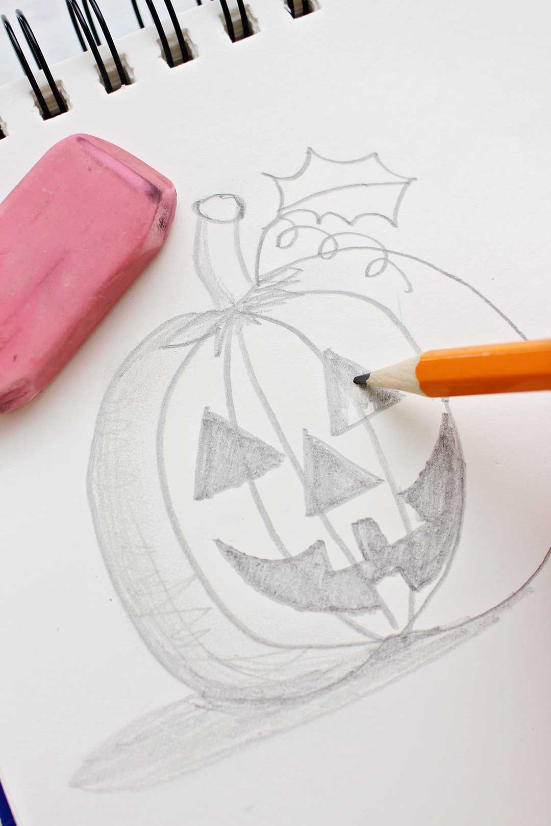 Pencil coloring in the eye of the jack-o-lantern pumpkin sketch.