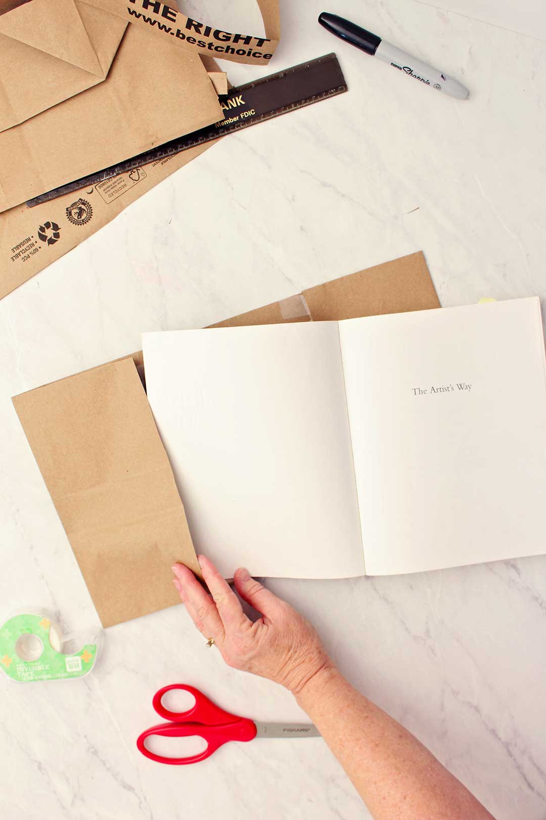 A hand sliding the inside book cover into the paper bag flap.