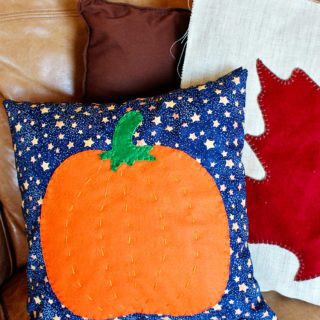 Two fall pillows resting on a tan leather couch.