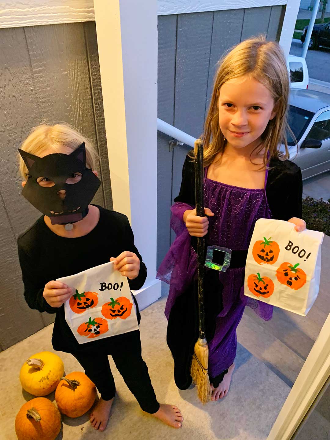 Two young girls, dressed as a black cat and a witch, go trick or treating.