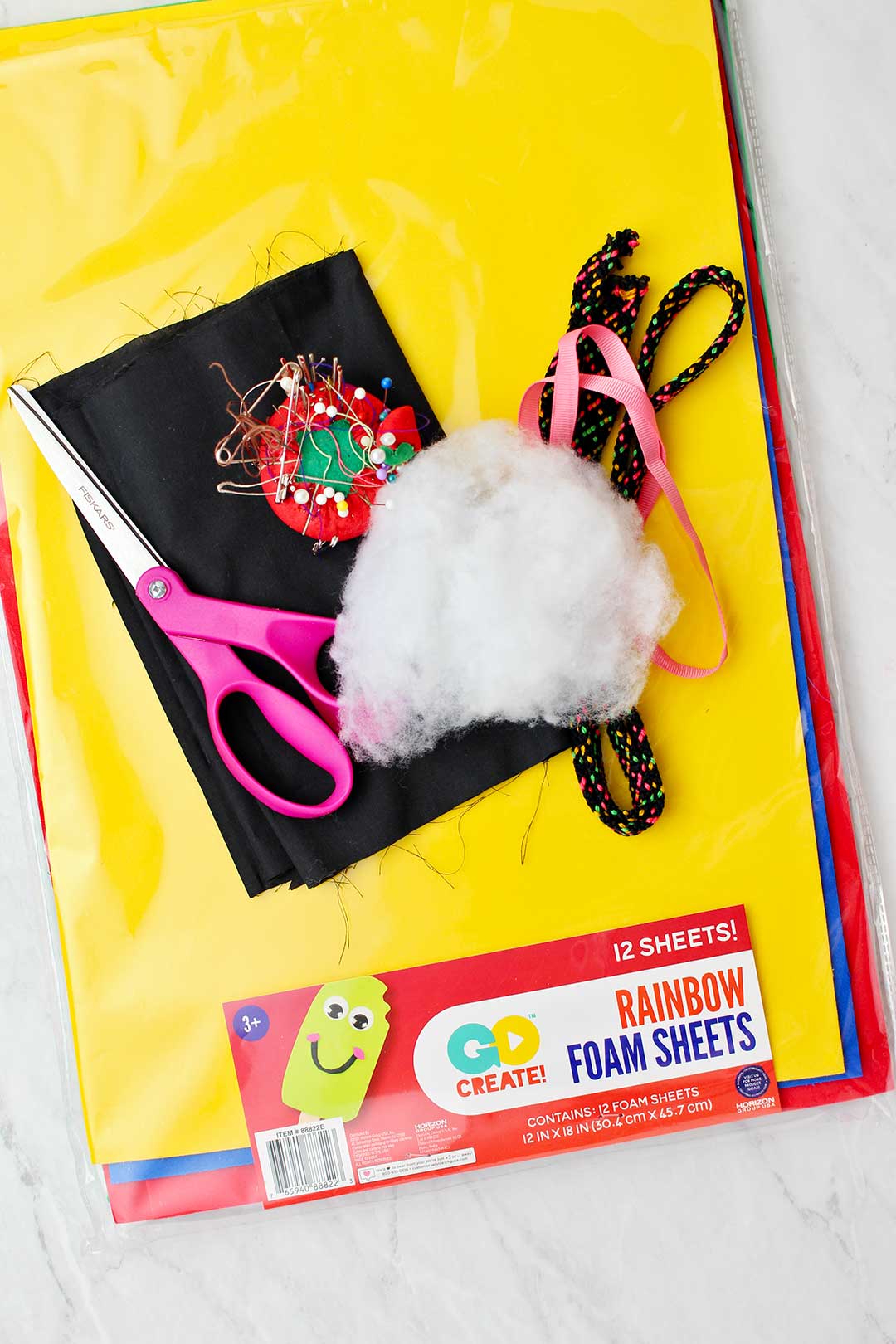 A packet of rainbow foam sheets and other various supplies to make black cat halloween costume.