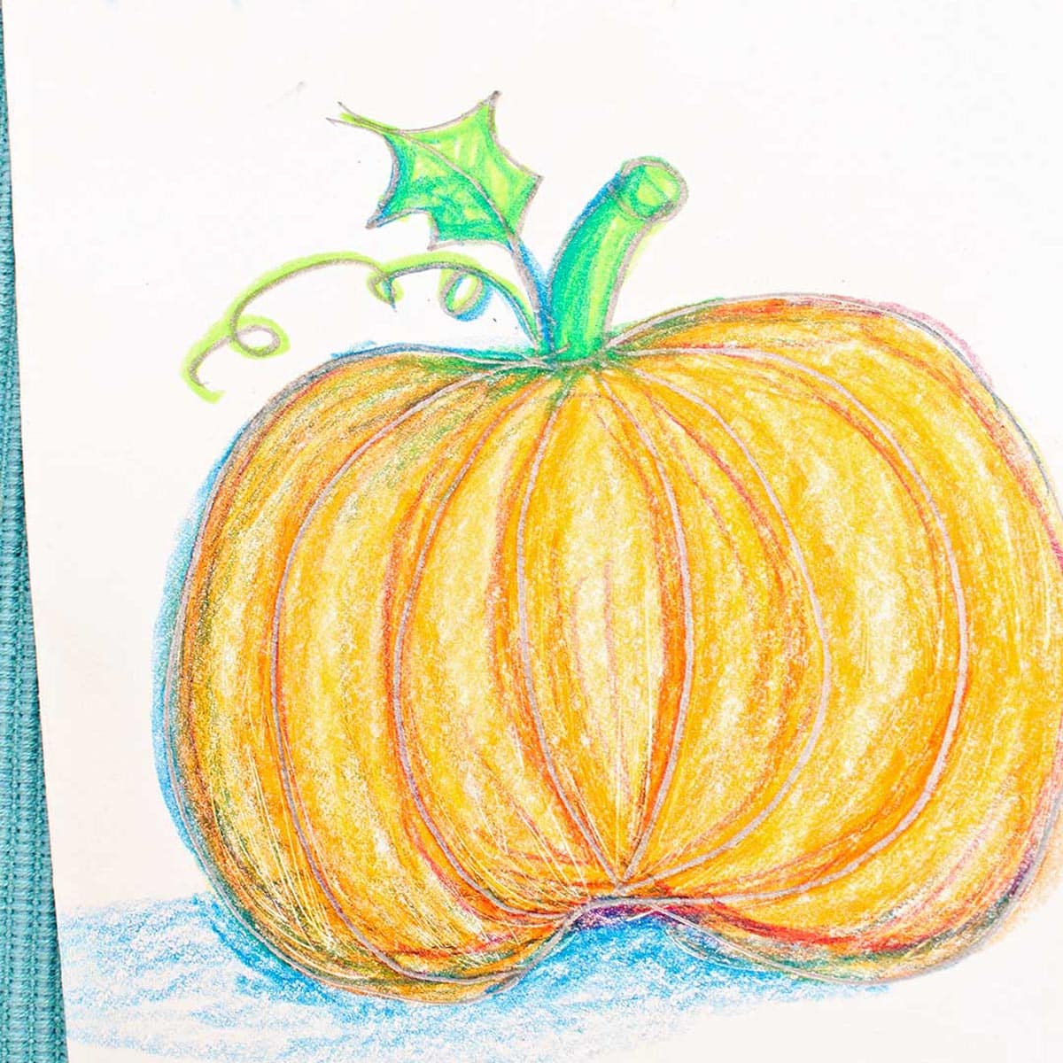 Colored pumpkin sketch greeting card resting on a blue woven placemat.