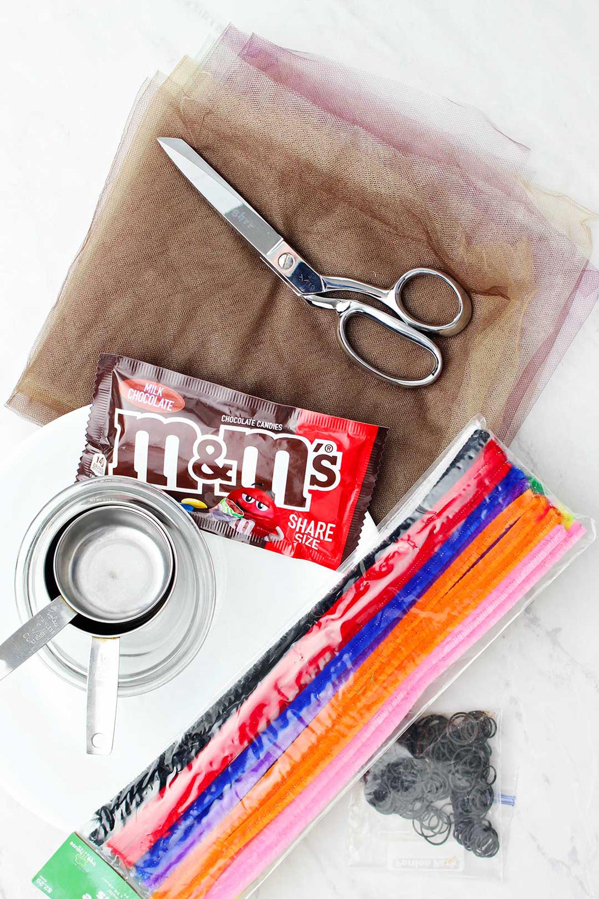 Supplies for Cute Turkey Thanksgiving Craft. Tulle, scissors, m&ms, measuring cups and pipe cleaners.