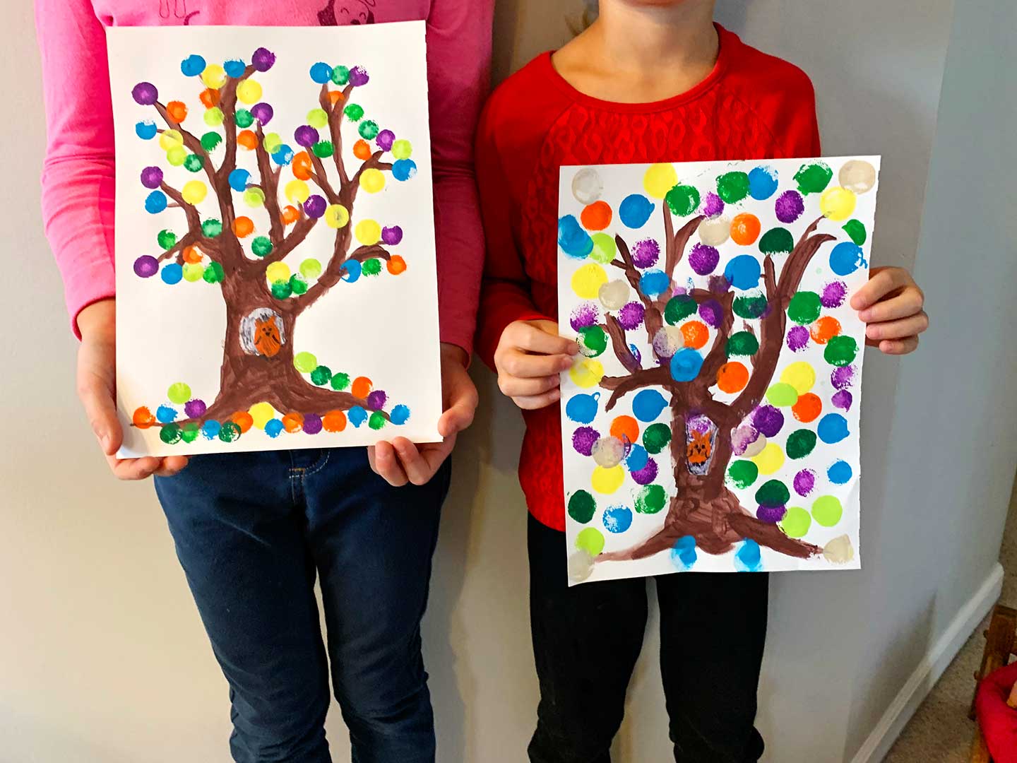 Two children holding their completed painted fall trees.