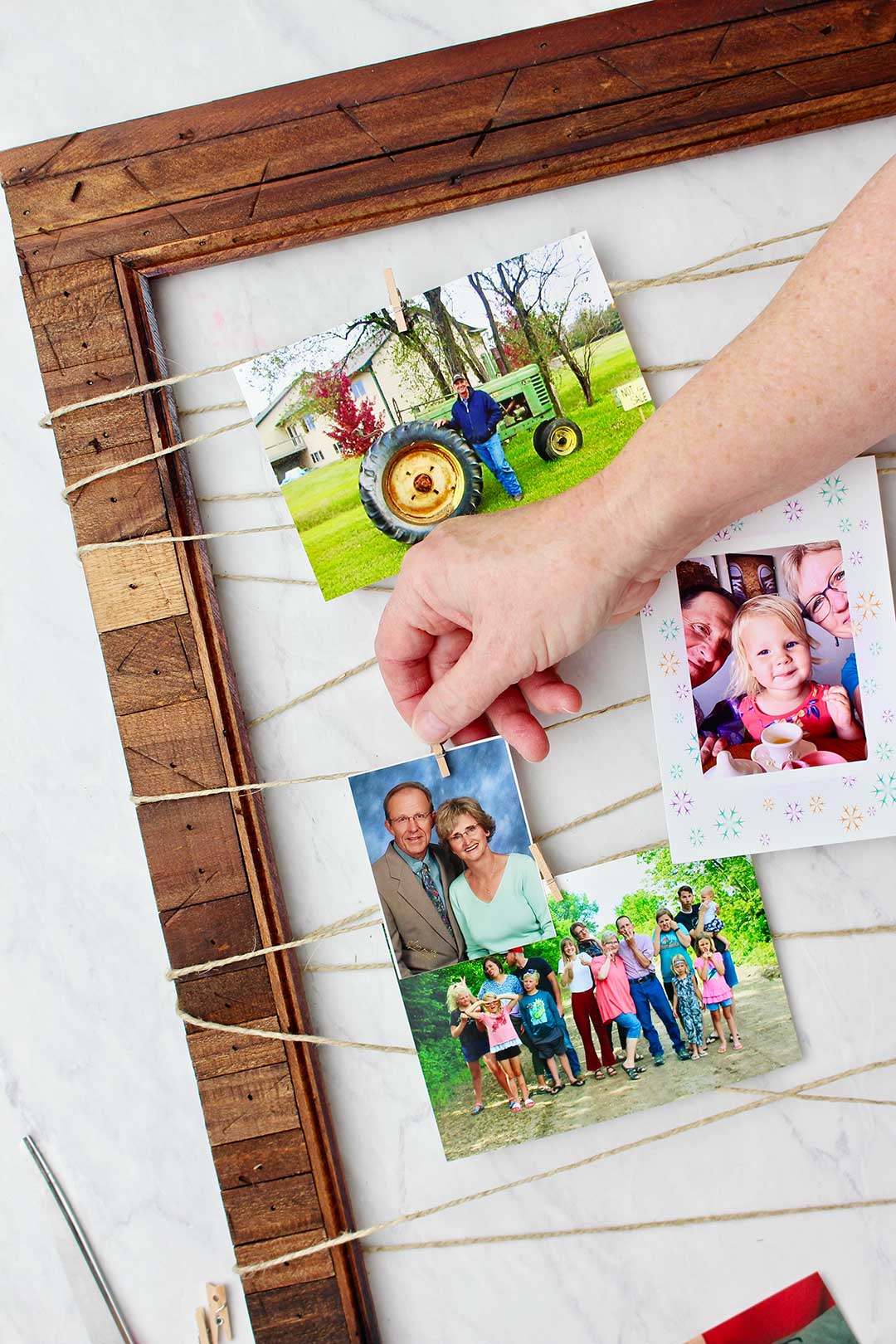 Hand clipping professional photo of couple on Upcycled Picture Frame with mini clothes pin.