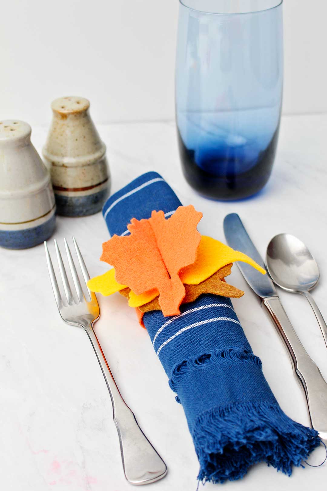 Completed Felt Thanksgiving Napkin Ring on a dark blue napkin with place setting.