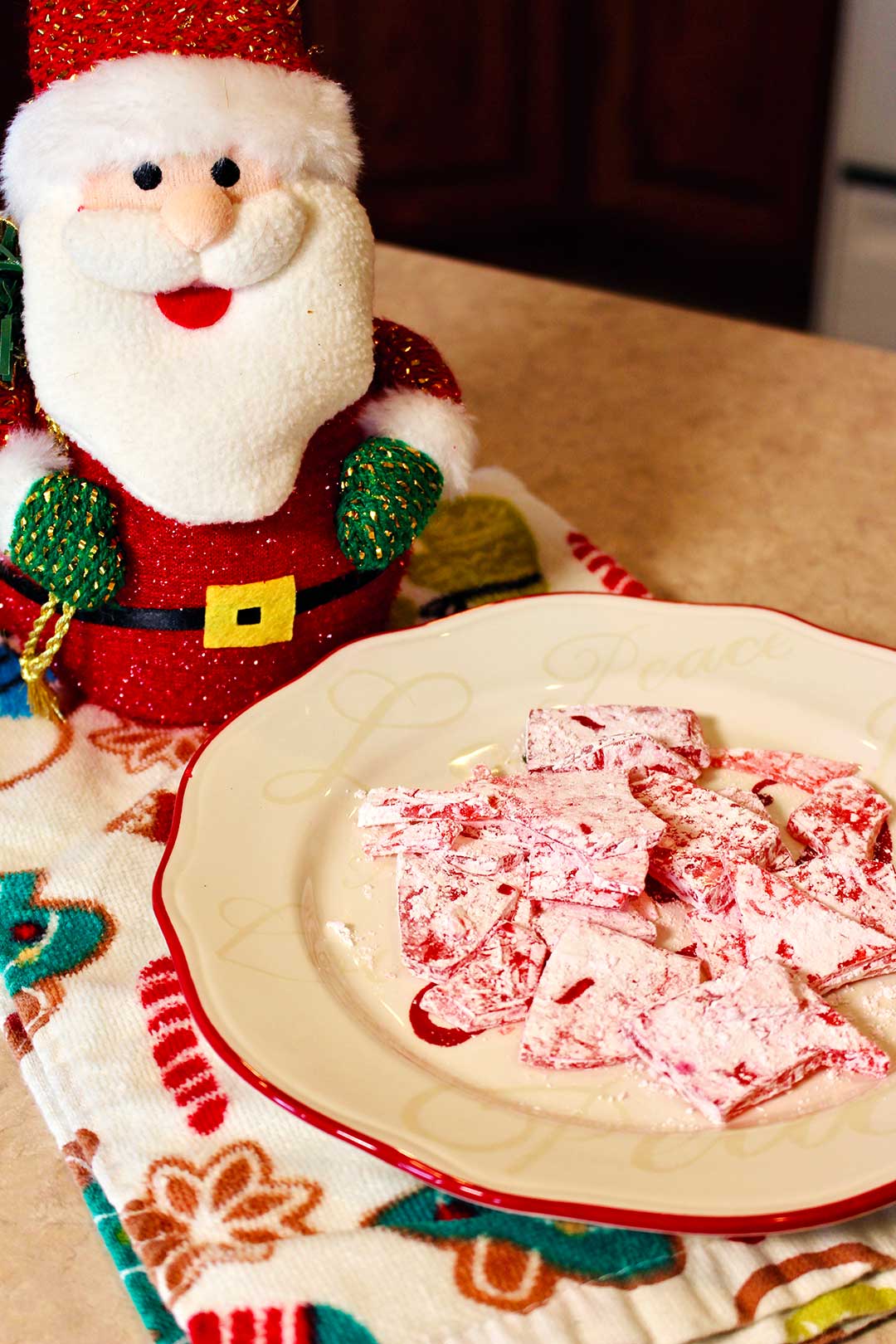 A Santa decoration and plate of cinnamon candies sitting on a festive hand towel