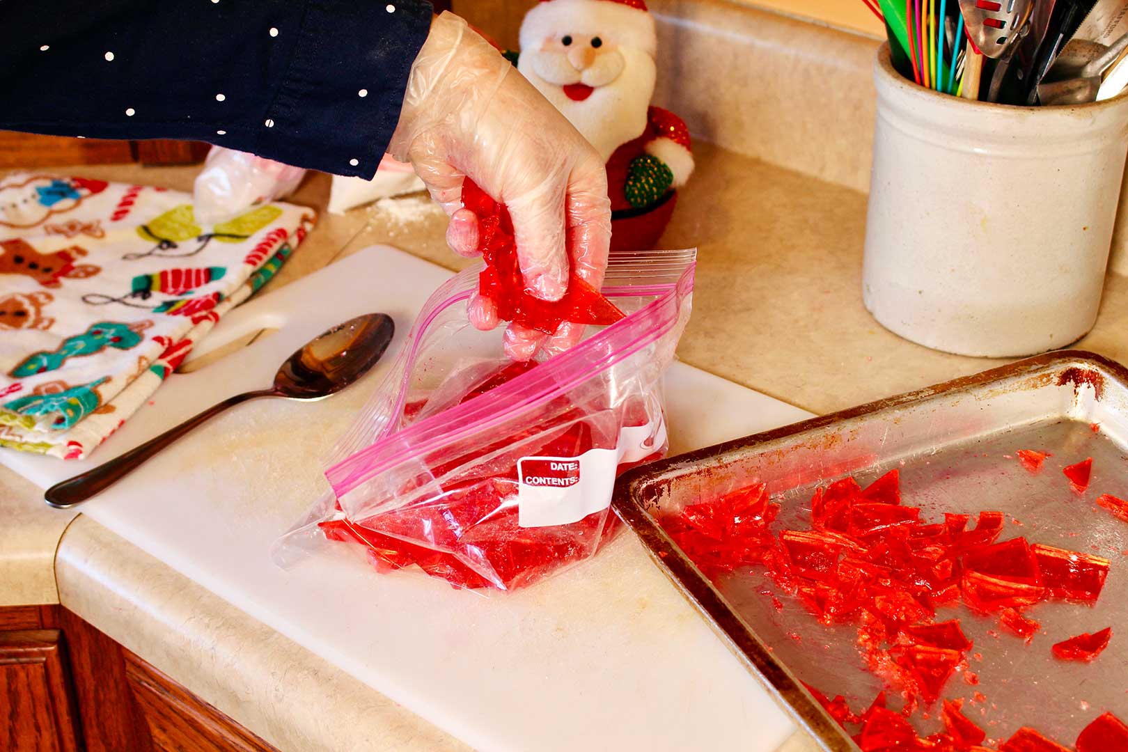 Hand placing broken pieces of homemade cinnamon candies in a ziplock bag.