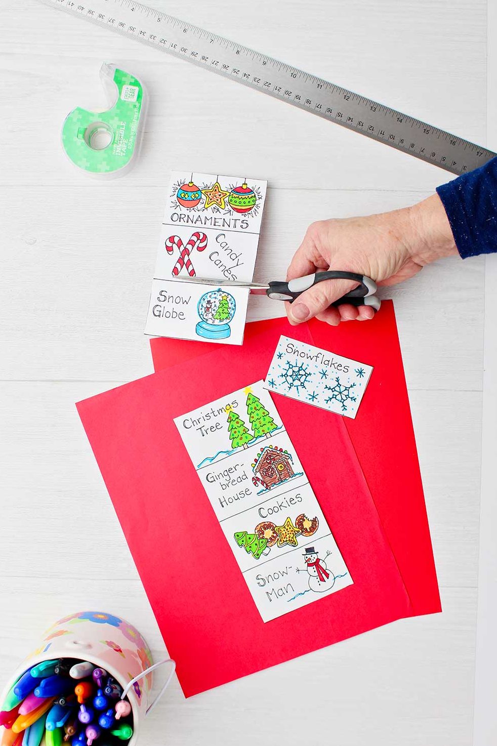A hand cutting holiday themed cards for headbands game after they had been colored in.