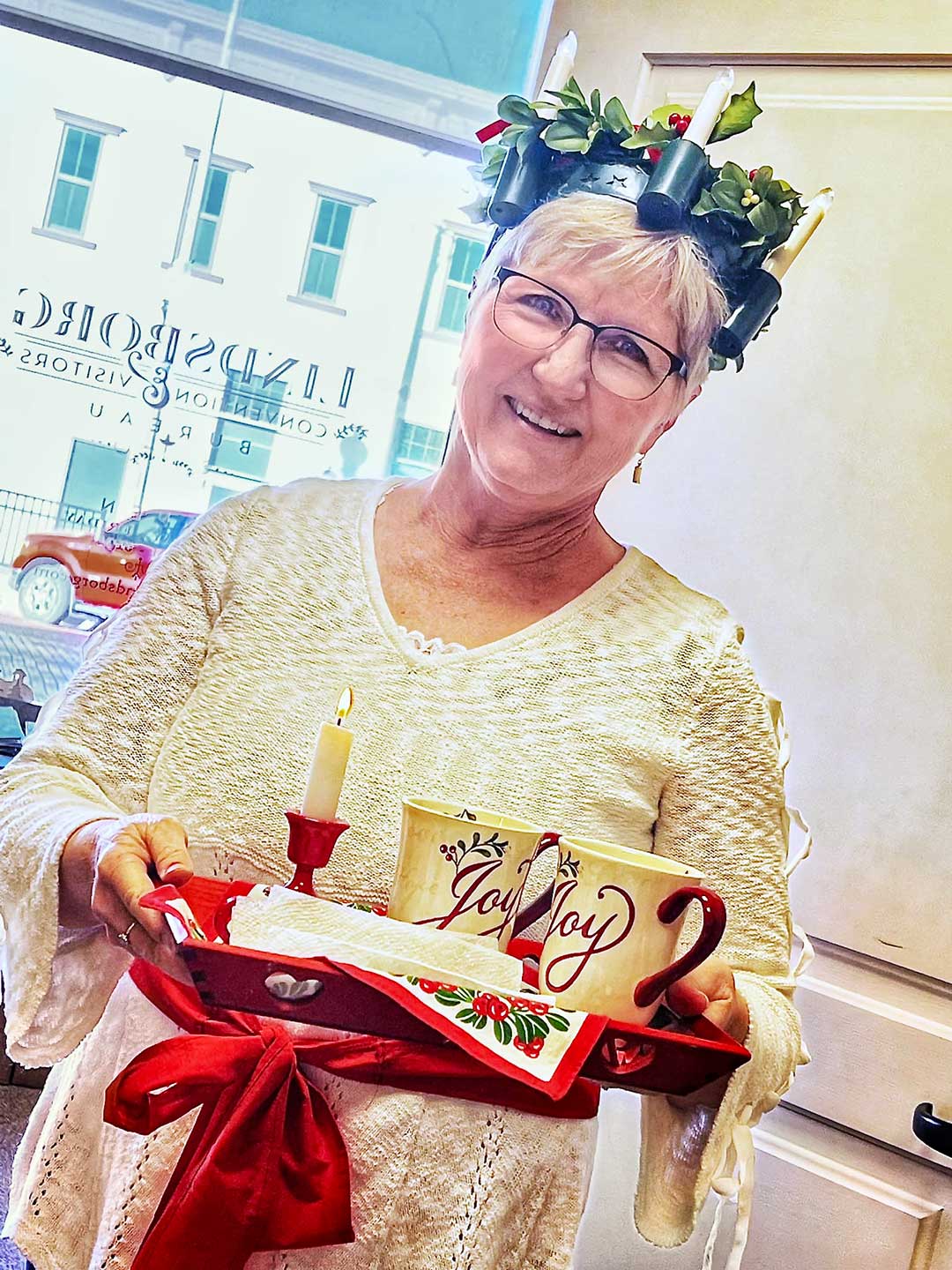 Image of Nana dressed as St. Lucia holding tray with Christmas mugs and a lit candle on it.
